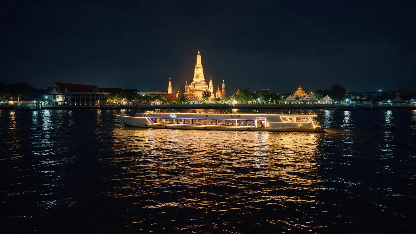 Illuminated dinner ship sailing on the Chao Phraya in the evening, with the floodlit Wat Arun in the background